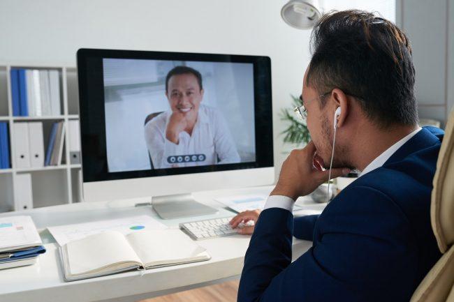 Entrepreneur sitting at his table and videocalling to business partner